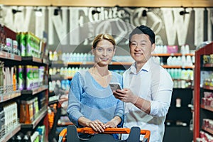 Family portrait of couple in supermarket shopping smiling and looking at camera