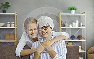 Portrait of happy mature lady together with her daughter or granddaughter at home