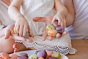 Family portrait of a happy mother, daughter and father posing in the kitchen during Breakfast, eating delicious macaroons, cakes,