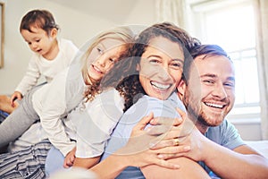 Family, portrait and happy smile in a home bedroom with children and parents together on bed for quality time. Man and