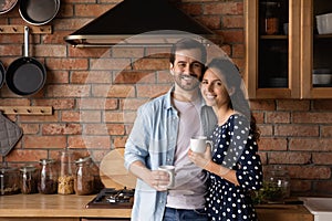Family portrait happy young couple drinking coffee in kitchen