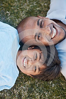 Family, portrait and lying on grass in backyard with father and kid together with love. Face, top view and dad with