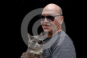 family portrait of middle aged man who holds his grey cat in hands on black background