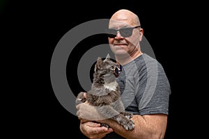 family portrait of middle aged man who holds his grey cat in hands on black background