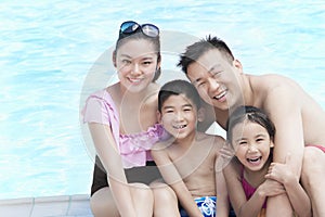 Family portrait, mother, father, daughter, and son, smiling by the pool