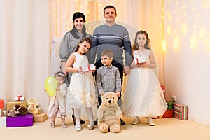 Family portrait - parents and children in home interior decorated with holiday lights and gifts