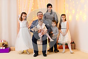 Family portrait - parents and children in home interior decorated with holiday lights and gifts