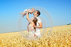 Family portrait. Picture of happy loving father, mother and their baby outdoors. Daddy, mom and child against summer blue sky.