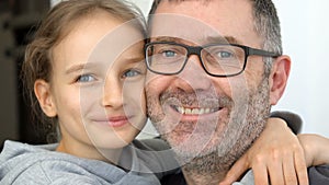 Family portrait of senior father and little blond daughters are hugging indoors and smiling, fathers day celebration