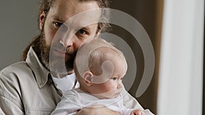 Family portrait serious Caucasian bearded dad father man holding hugging small infant newborn girl boy kid daughter son