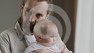 Family portrait serious Caucasian bearded dad father man holding hugging small infant newborn girl boy kid daughter son