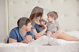 Family portrait of three people On Parents Bed Wearing Pajamas