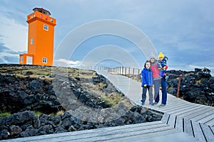Family posing in front of lighthouse in lava field in beautiful nature in Snaefellsjokull National Park in Iceland