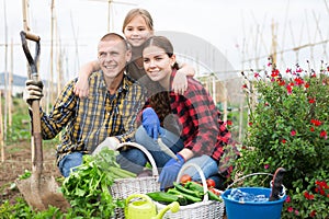 Family posing in garden with gathered vegetables
