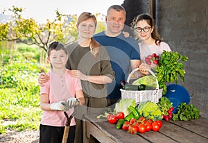 Family posing in garden with picked vegetables