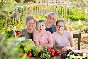 Family posing in garden with picked vegetables