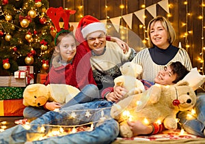 Family posing in new year or christmas decoration. Children and parents. Holiday lights and gifts, Christmas tree decorated with