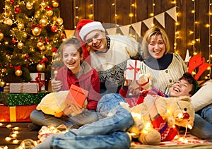 Family posing in new year or christmas decoration. Children and parents. Holiday lights and gifts, Christmas tree decorated with