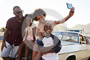 Family Posing For Selfie Next To Car Packed For Road Trip photo