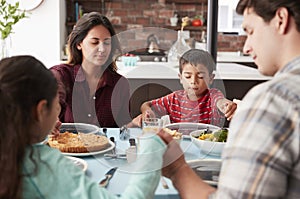 Family Praying Before Meal Around Table At Home photo
