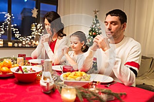 Family praying before meal at christmas dinner