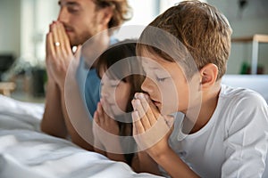 Family praying near bed at home
