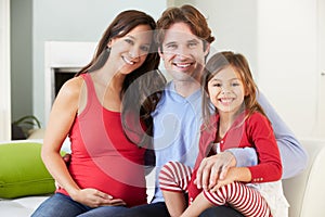 Family With Pregnant Mother Relaxing On Sofa Together