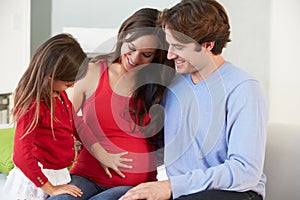 Family With Pregnant Mother Relaxing On Sofa Together