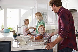 Family Preparing Roast Turkey Meal In Kitchen Together
