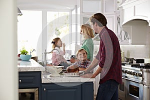 Family Preparing Roast Turkey Meal In Kitchen Together