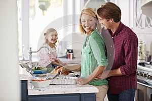 Family Preparing Roast Turkey Meal In Kitchen Together