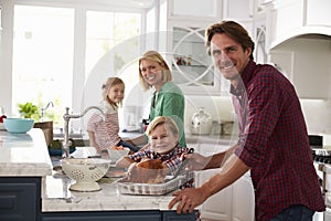 Family Preparing Roast Turkey Meal In Kitchen Together