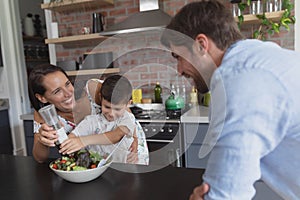 Family preparing vegetable salad in kitchen at home