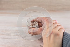 Family problem - alcoholism: a shot of vodka battered men, the hand of the woman holds the man`s hand, forbidding to drink alcoho