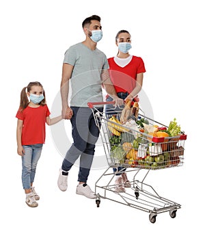 Family with protective masks and shopping cart full of groceries on white background