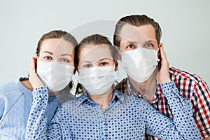 Family in protective medical masks. Mother, father, daughter protect themselves from the virus at home. Coronavirus