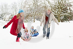 Famiglia tirando slitta attraverso la neve 