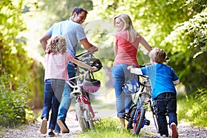 Family Pushing Bikes Along Country Track