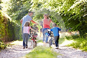 Famiglia spingendo biciclette lungo Paesi orologio 