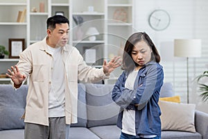 Family quarrel, asian couple man and woman yelling at each other, family conflict, asians at home standing angry in