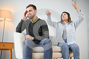 Family quarrel, man and woman sitting on sofa at home. angry woman yells at her husband