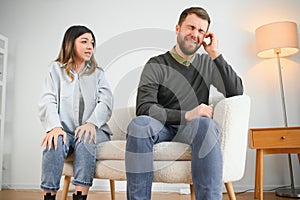 Family quarrel, man and woman sitting on sofa at home. angry woman yells at her husband