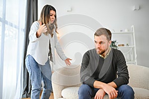 Family quarrel, man and woman sitting on sofa at home. angry woman yells at her husband