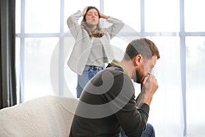 Family quarrel, man and woman sitting on sofa at home. angry woman yells at her husband