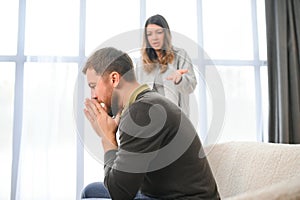 Family quarrel, man and woman sitting on sofa at home. angry woman yells at her husband