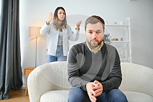 Family quarrel, man and woman sitting on sofa at home. angry woman yells at her husband