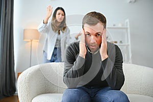 Family quarrel, man and woman sitting on sofa at home. angry woman yells at her husband