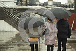 Family in the rain. People with umbrellas on the street. Walk around the city in rainy weather