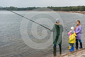 family in raincoats and rubber boots fishing together