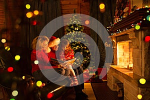 Family read stories sitting on sofa in front of fireplace in Christmas decorated house interior